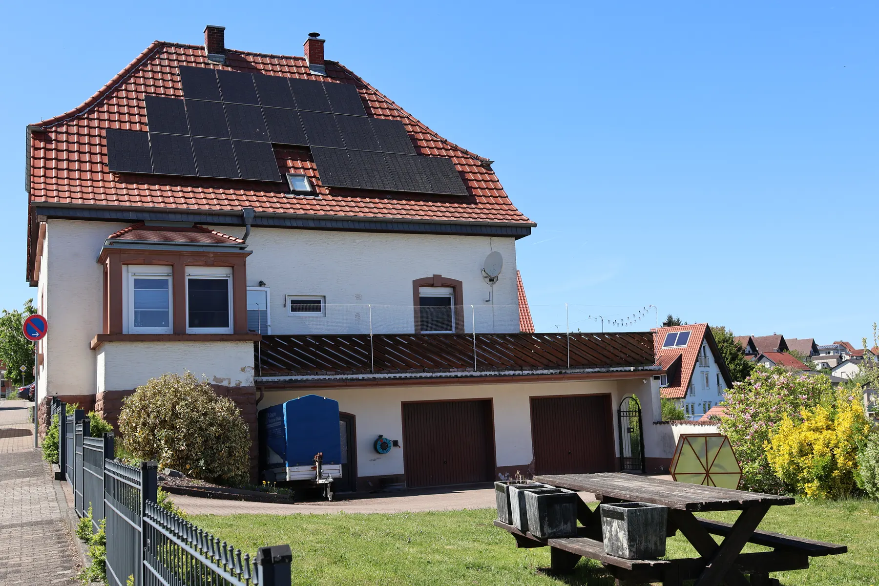 The house at Bahnhofstraße 25 seen from the garden, with solar panels on the red tile roof