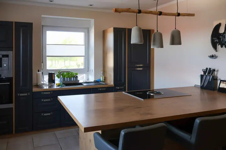 Kitchen with navy cabinets, wood-look worktops and a large island with induction cooktop